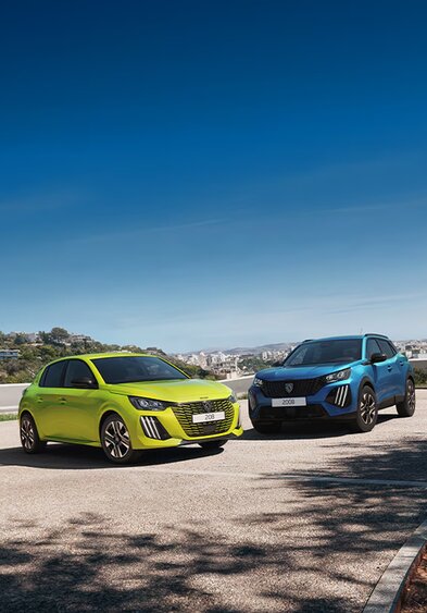 Ein Peugeot 208 und 2008 auf einer Anhöhe mit Stadtpanorama im Hintergrund.